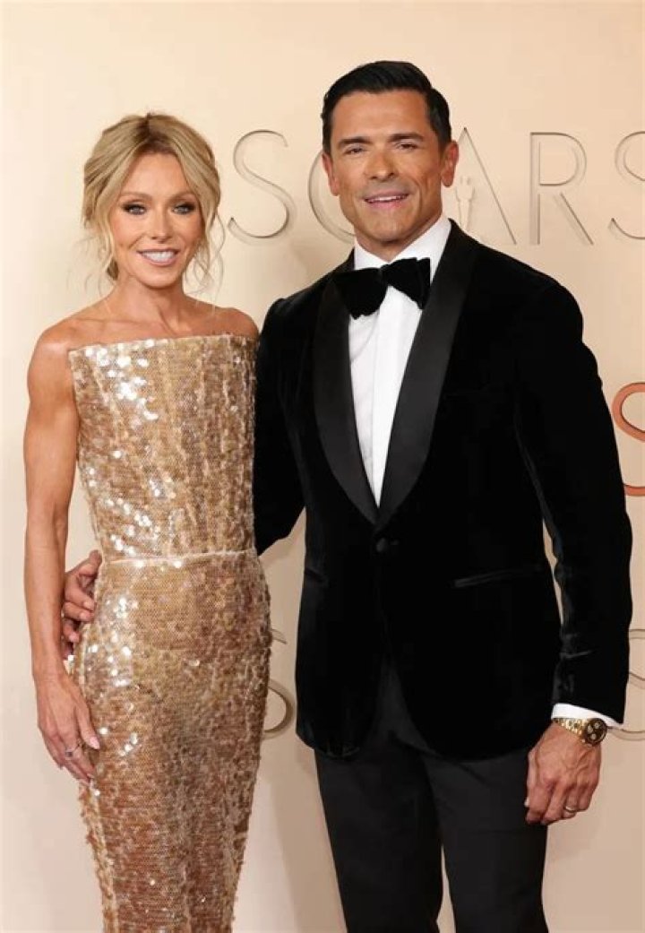 Kelly Ripa on the Oscars red carpet wearing a black dress, dark eyeshadow, and her signature blond hair